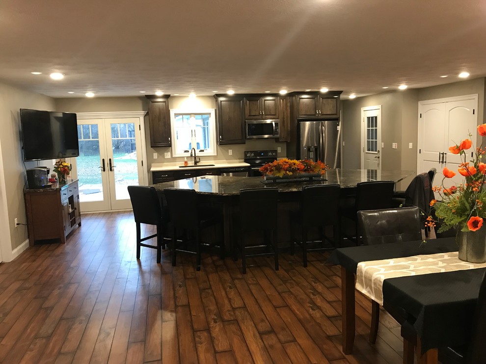 Example of a large classic galley dark wood floor and brown floor open concept kitchen design with raised-panel cabinets, granite countertops, stainless steel appliances, an undermount sink, dark wood cabinets and an island