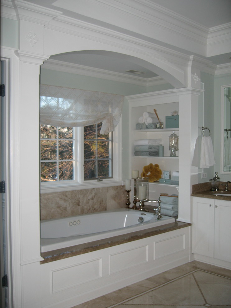 Photo of a large traditional master bathroom in New York with an undermount sink, recessed-panel cabinets, white cabinets, marble benchtops, a hot tub, an alcove shower, a two-piece toilet, beige tile, stone tile, green walls and marble floors.