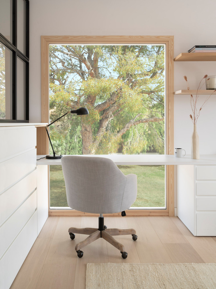 Foto di uno studio minimal con parquet chiaro, scrivania incassata e pavimento beige