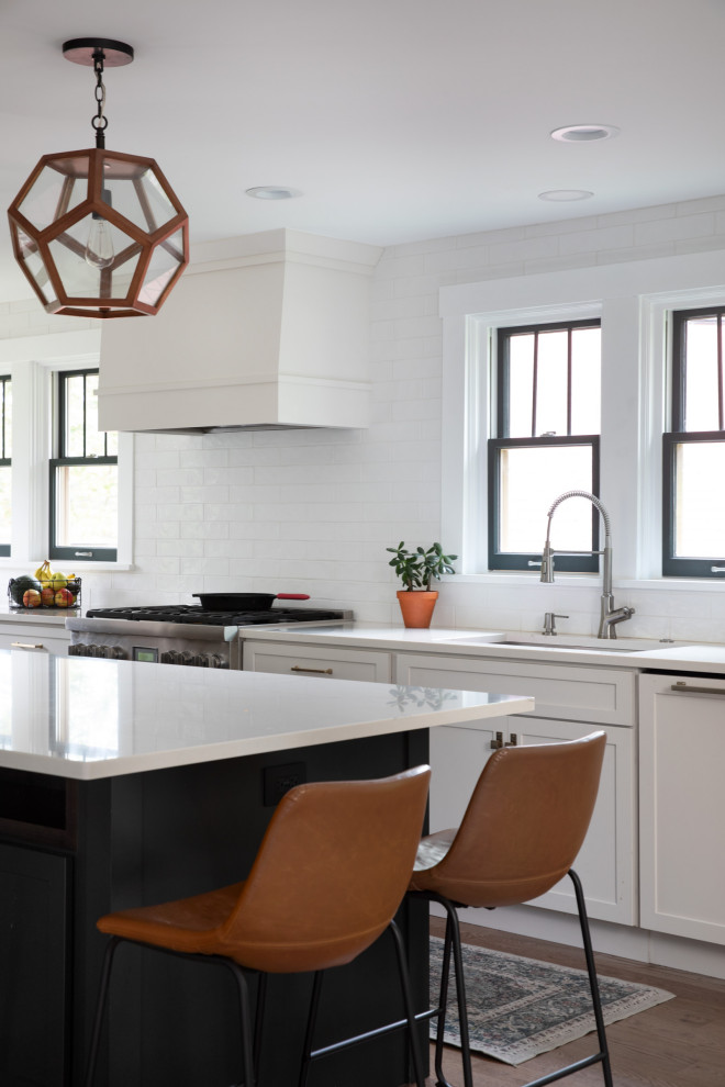 Inspiration for a transitional l-shaped medium tone wood floor and brown floor eat-in kitchen remodel in Other with a drop-in sink, shaker cabinets, white cabinets, quartzite countertops, white backsplash, subway tile backsplash, stainless steel appliances, an island and white countertops