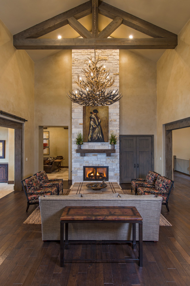 Country formal living room in Austin with beige walls, dark hardwood floors, a standard fireplace, a stone fireplace surround and no tv.