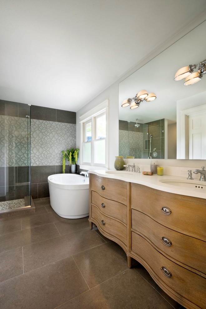 Inspiration for a large transitional master bathroom in Portland with flat-panel cabinets, medium wood cabinets, a freestanding tub, a corner shower, gray tile, white walls, an undermount sink, stone tile, cement tiles and solid surface benchtops.