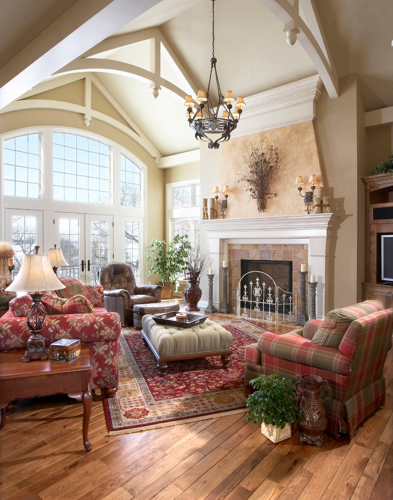 Large traditional formal open concept living room in Milwaukee with brown walls, light hardwood floors, a standard fireplace, a wall-mounted tv and a tile fireplace surround.