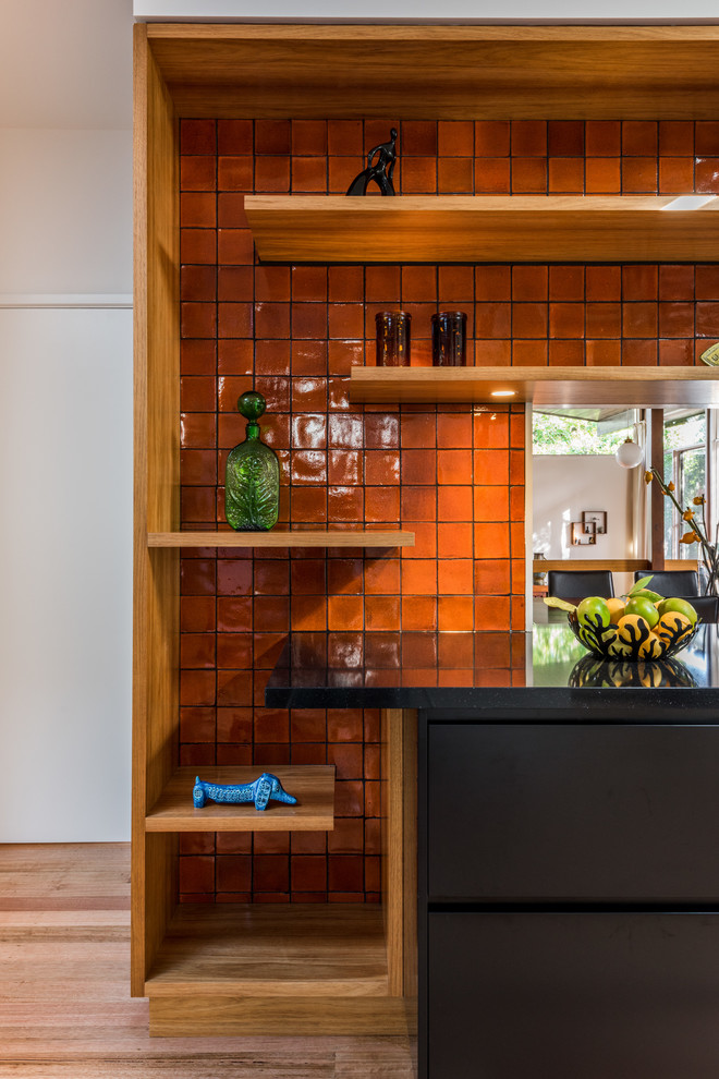 Photo of a l-shaped eat-in kitchen in Melbourne with an undermount sink, orange splashback, ceramic splashback, stainless steel appliances and medium hardwood floors.