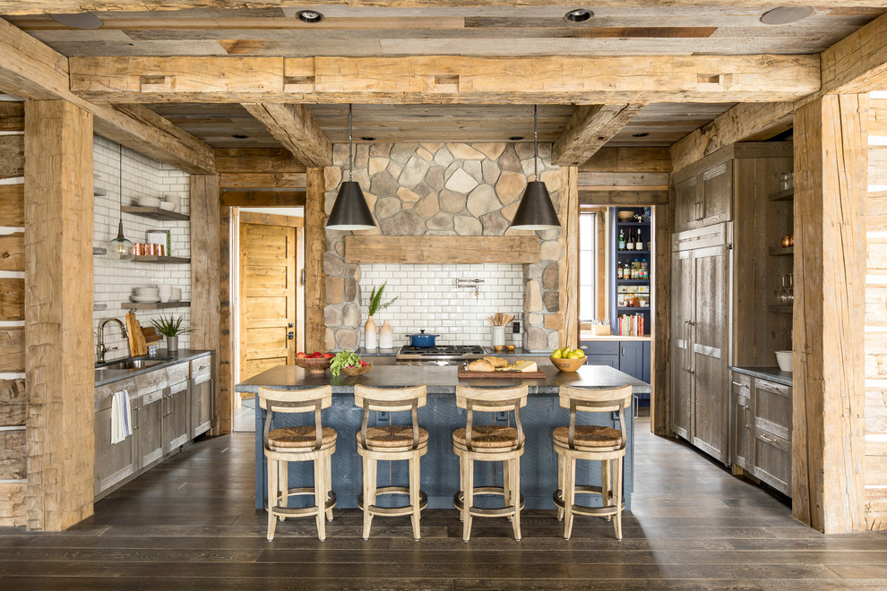 Eat-in kitchen - large rustic u-shaped dark wood floor and brown floor eat-in kitchen idea in Minneapolis with an undermount sink, shaker cabinets, medium tone wood cabinets, soapstone countertops, white backsplash, ceramic backsplash, paneled appliances and an island