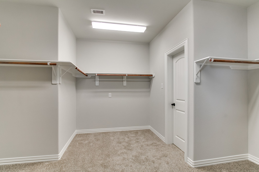 This is an example of a traditional walk-in wardrobe in Houston with carpet.