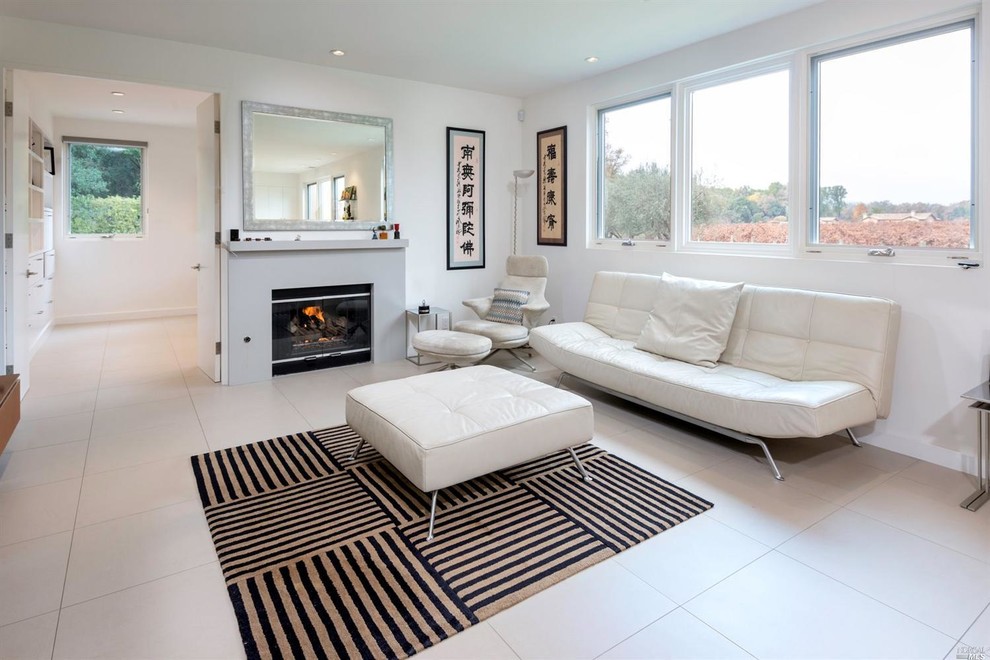 This is an example of a small contemporary open concept family room in San Francisco with a wall-mounted tv, white walls, porcelain floors, a standard fireplace and a stone fireplace surround.