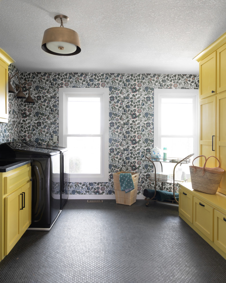 This is an example of a galley dedicated laundry room in Kansas City with recessed-panel cabinets, yellow cabinets, quartz benchtops, multi-coloured walls, ceramic floors, a side-by-side washer and dryer, black floor, black benchtop and wallpaper.