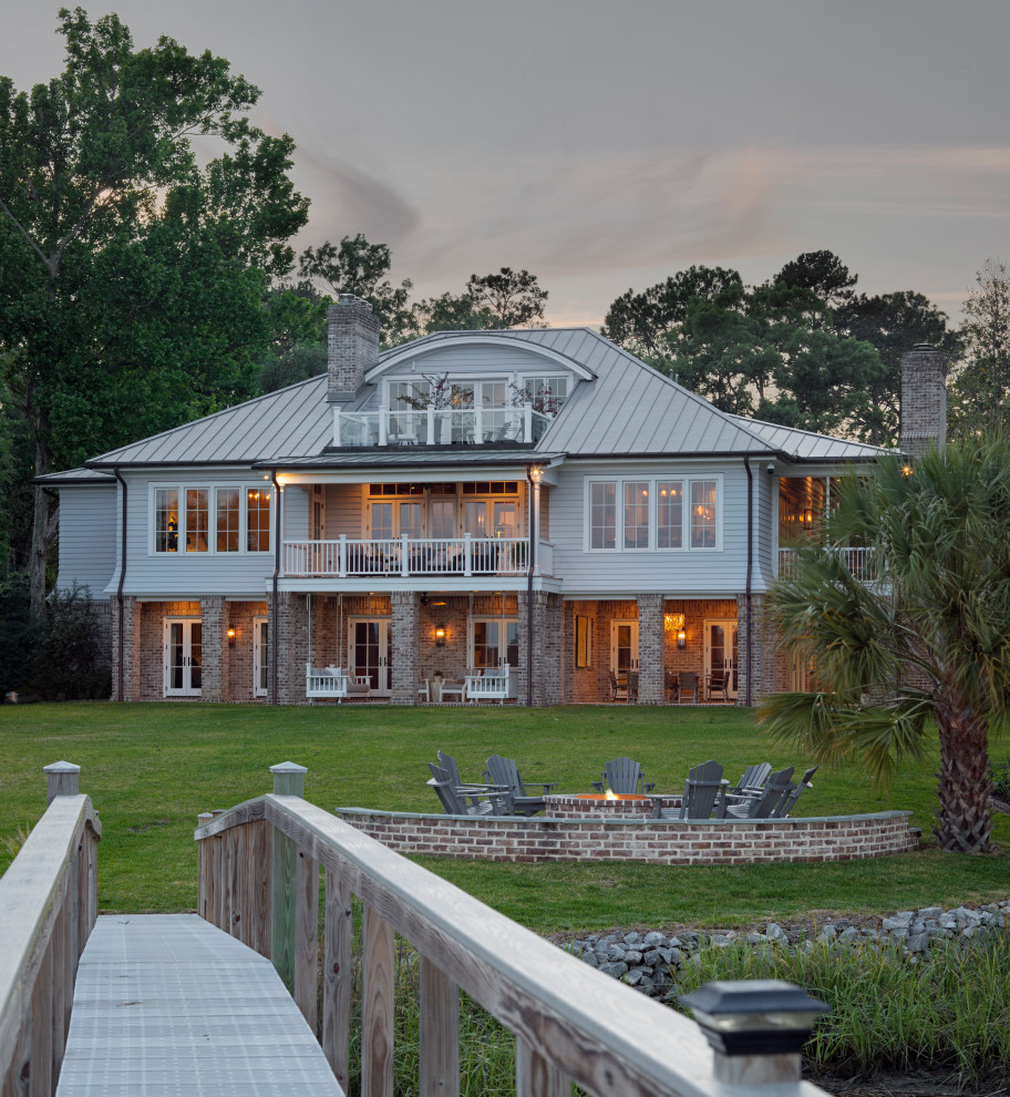 Aménagement d'une grande façade de maison multicolore bord de mer en brique et planches et couvre-joints à deux étages et plus avec un toit en métal et un toit gris.