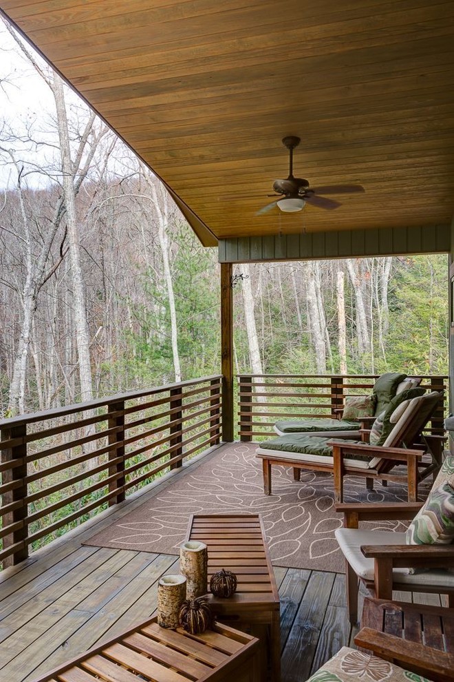 Example of a mid-sized mountain style backyard deck design with a roof extension