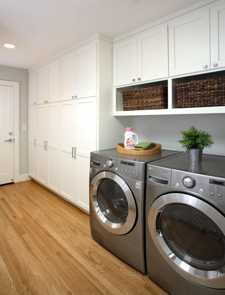 This is an example of a traditional laundry room in San Francisco with white cabinets.
