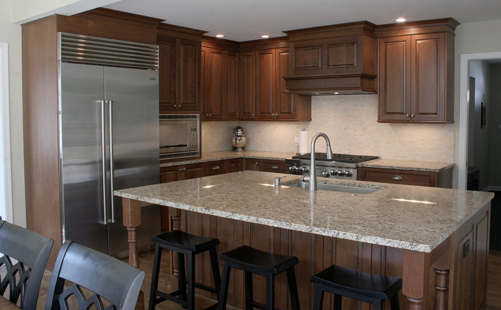 Eat-in kitchen - large transitional l-shaped dark wood floor and brown floor eat-in kitchen idea in Chicago with an undermount sink, raised-panel cabinets, medium tone wood cabinets, granite countertops, beige backsplash, subway tile backsplash, stainless steel appliances and an island