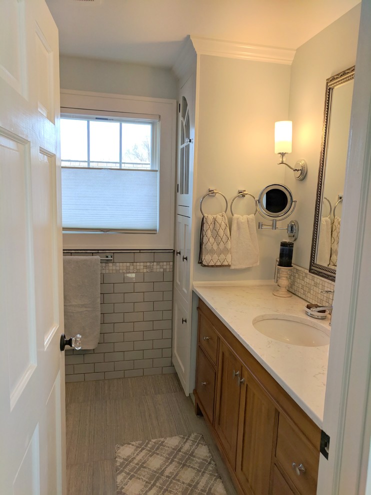 This is an example of a small transitional master bathroom in Cleveland with shaker cabinets, medium wood cabinets, gray tile, ceramic tile, blue walls, porcelain floors, an undermount sink, engineered quartz benchtops, grey floor and white benchtops.