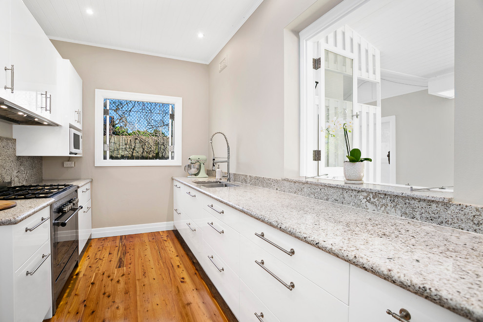 Inspiration for a mid-sized transitional galley separate kitchen in Sydney with a double-bowl sink, shaker cabinets, white cabinets, quartz benchtops, stainless steel appliances, medium hardwood floors and multiple islands.