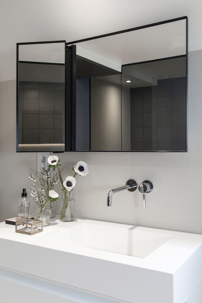 This is an example of a mid-sized contemporary master bathroom in Paris with a drop-in tub, white walls, flat-panel cabinets, white cabinets, an open shower, a wall-mount toilet, black and white tile, ceramic tile, concrete floors, a console sink, solid surface benchtops, grey floor, a hinged shower door, white benchtops, a shower seat, a double vanity and a floating vanity.