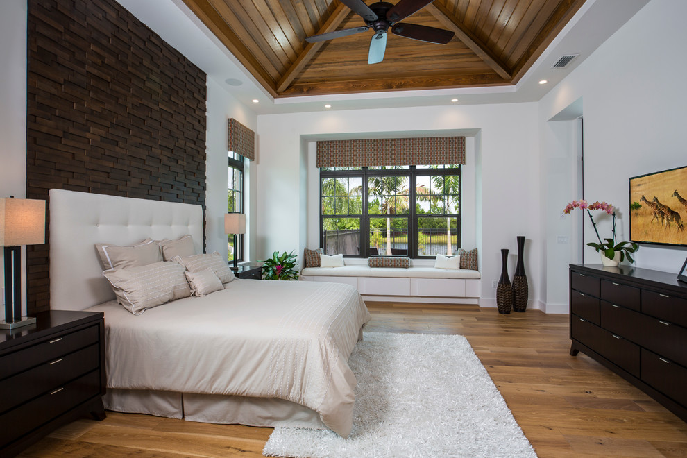 Tropical master bedroom in Tampa with white walls and medium hardwood floors.