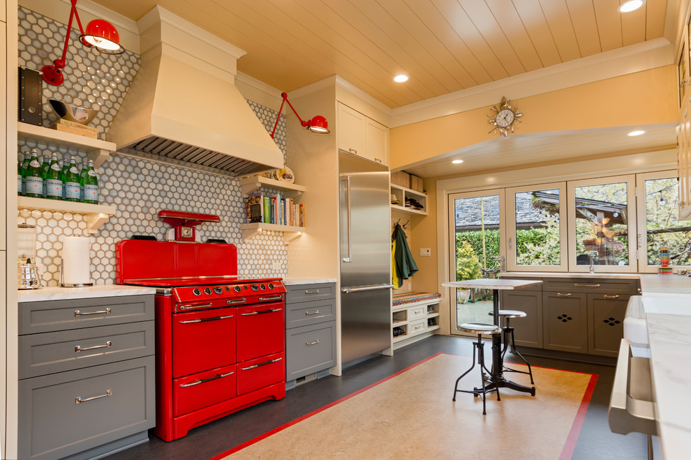 Example of a large transitional u-shaped linoleum floor and multicolored floor kitchen pantry design in Seattle with a farmhouse sink, shaker cabinets, gray cabinets, solid surface countertops, gray backsplash, porcelain backsplash, colored appliances and a peninsula