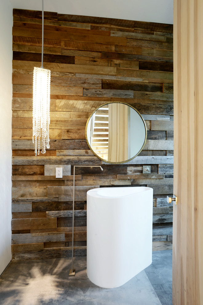 Mid-sized contemporary powder room in Los Angeles with a pedestal sink, brown walls and concrete floors.