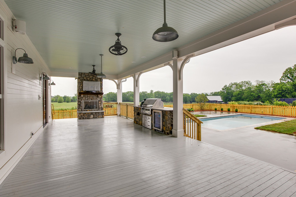 Large country backyard verandah in Nashville with an outdoor kitchen, decking and a roof extension.