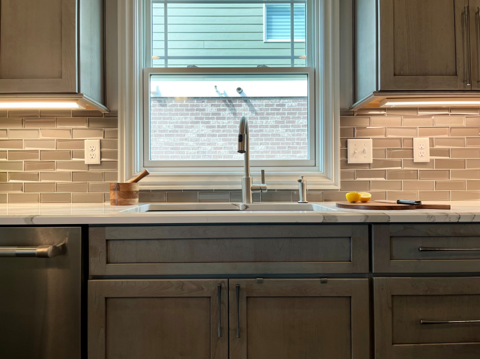 Inspiration for a mid-sized transitional l-shaped dark wood floor and brown floor eat-in kitchen remodel with an undermount sink, gray cabinets, quartz countertops, glass tile backsplash, stainless steel appliances, an island, white backsplash and beige countertops