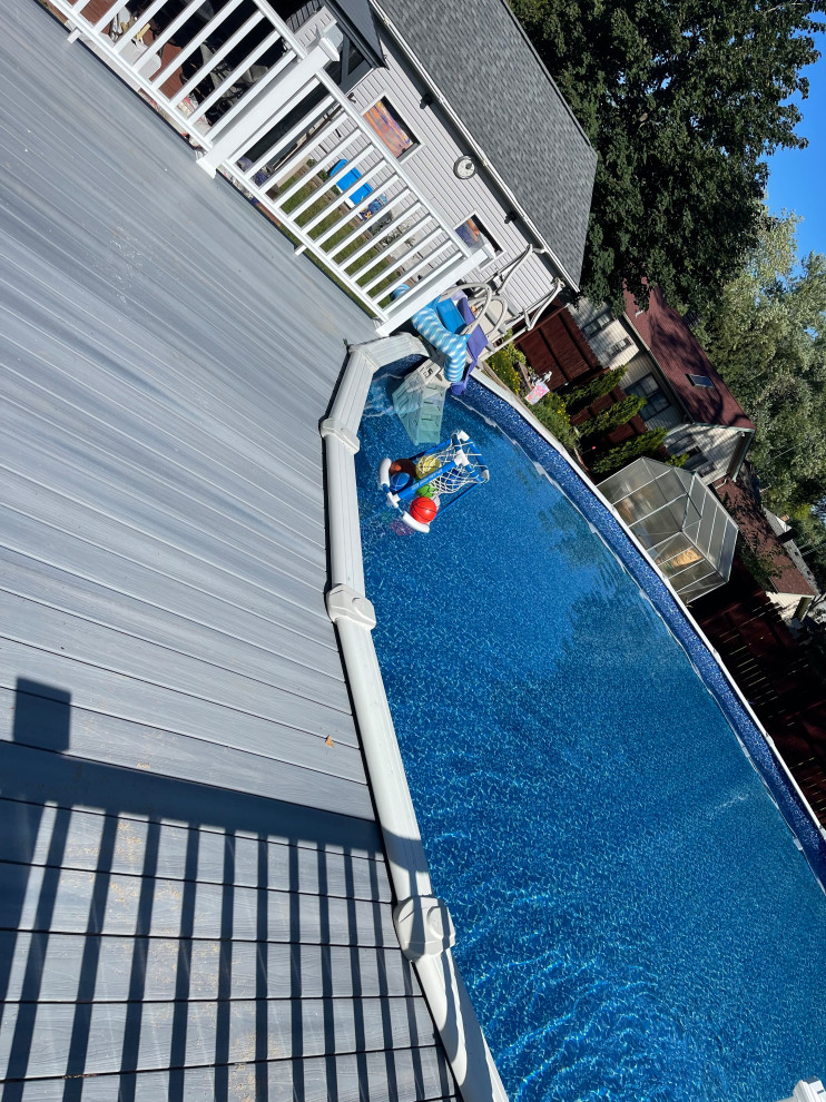 Example of a large beach style backyard custom-shaped aboveground pool design in Chicago with decking