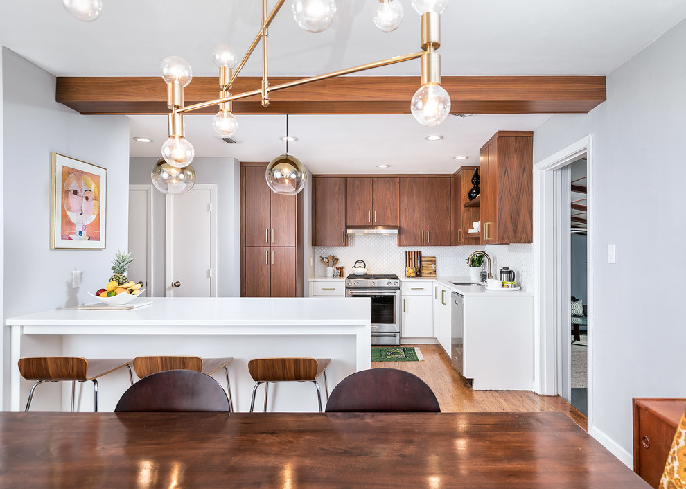Small midcentury l-shaped separate kitchen in Miami with a single-bowl sink, flat-panel cabinets, light wood cabinets, quartz benchtops, white splashback, mosaic tile splashback, stainless steel appliances, light hardwood floors, a peninsula and brown floor.