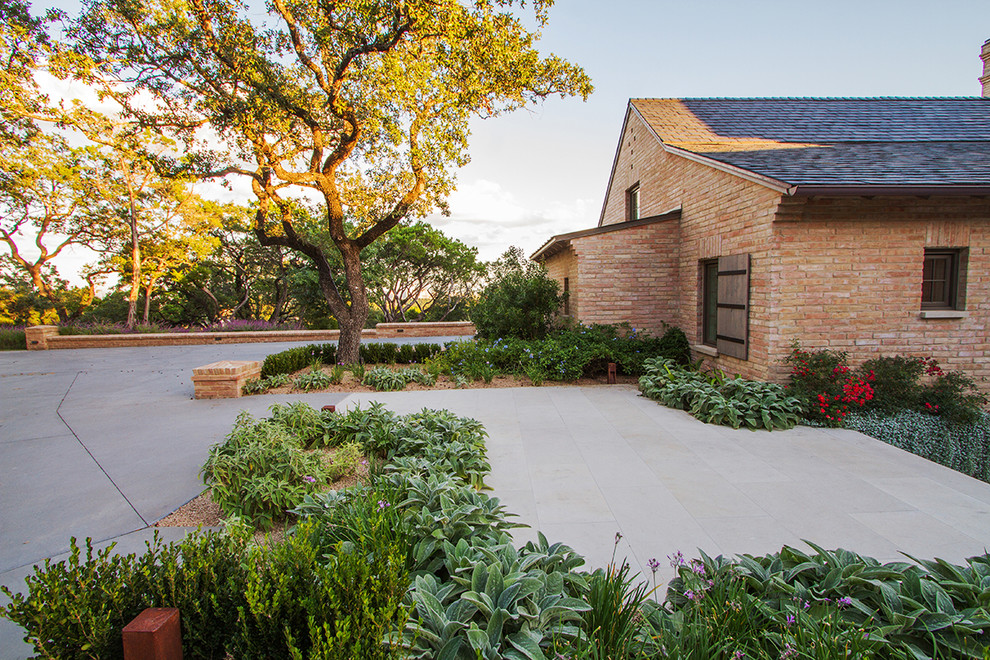 Large country front yard full sun formal garden in Austin with a garden path and concrete pavers for spring.