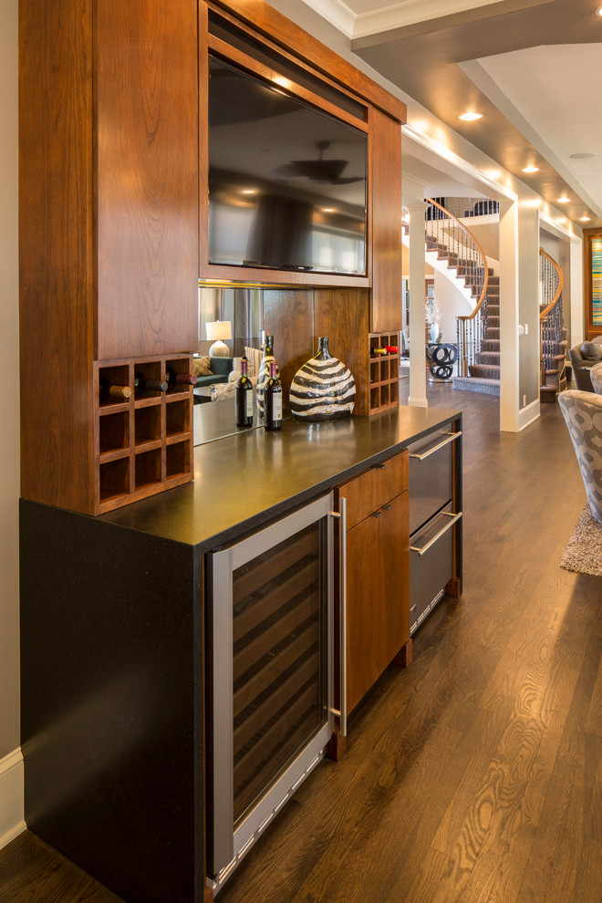 Small traditional single-wall wet bar in Kansas City with flat-panel cabinets, medium wood cabinets and dark hardwood floors.