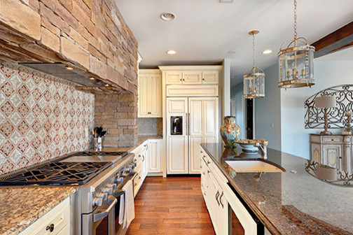 Inspiration for a large rustic l-shaped open concept kitchen remodel in Louisville with raised-panel cabinets, beige cabinets, granite countertops, beige backsplash, ceramic backsplash and an island