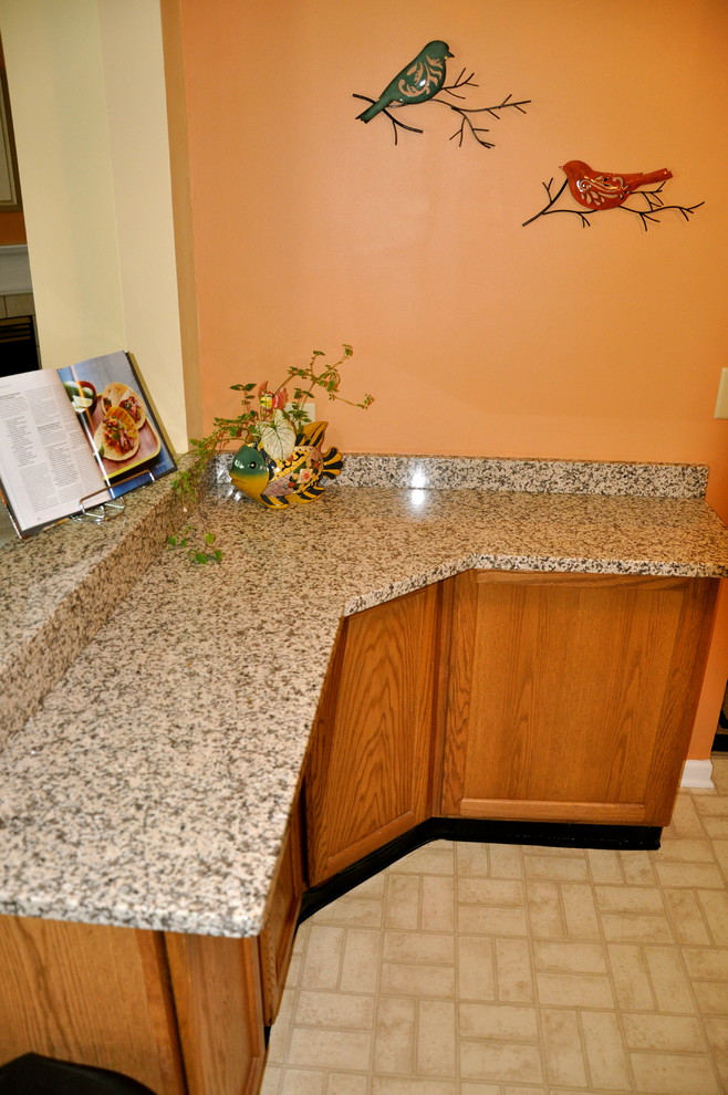 Enclosed kitchen - small transitional u-shaped linoleum floor enclosed kitchen idea in Cincinnati with recessed-panel cabinets, medium tone wood cabinets, granite countertops and orange walls