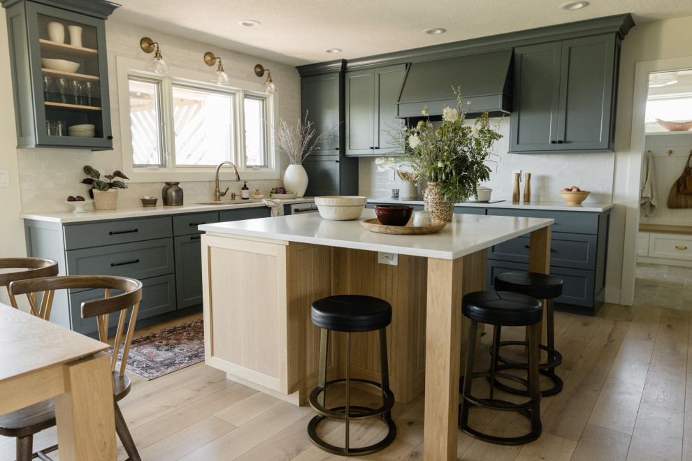 Klassische Küche in U-Form mit Unterbauwaschbecken, Küchenrückwand in Weiß, weißen Elektrogeräten, hellem Holzboden, Kücheninsel und weißer Arbeitsplatte in Sonstige
