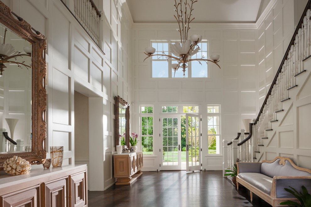 Huge transitional dark wood floor foyer photo in New York with white walls and a glass front door