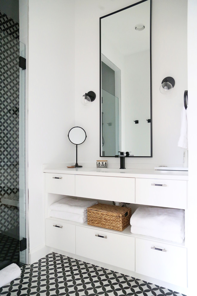 Photo of a contemporary bathroom in Other with flat-panel cabinets, white cabinets, black and white tile, white walls, an undermount sink, black floor and white benchtops.