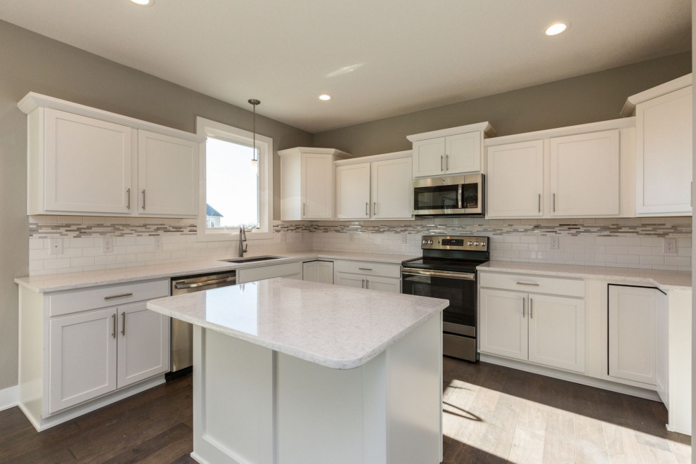 Example of a mid-sized transitional medium tone wood floor and brown floor eat-in kitchen design with an undermount sink, shaker cabinets, white cabinets, quartz countertops, multicolored backsplash, subway tile backsplash, stainless steel appliances, an island and white countertops