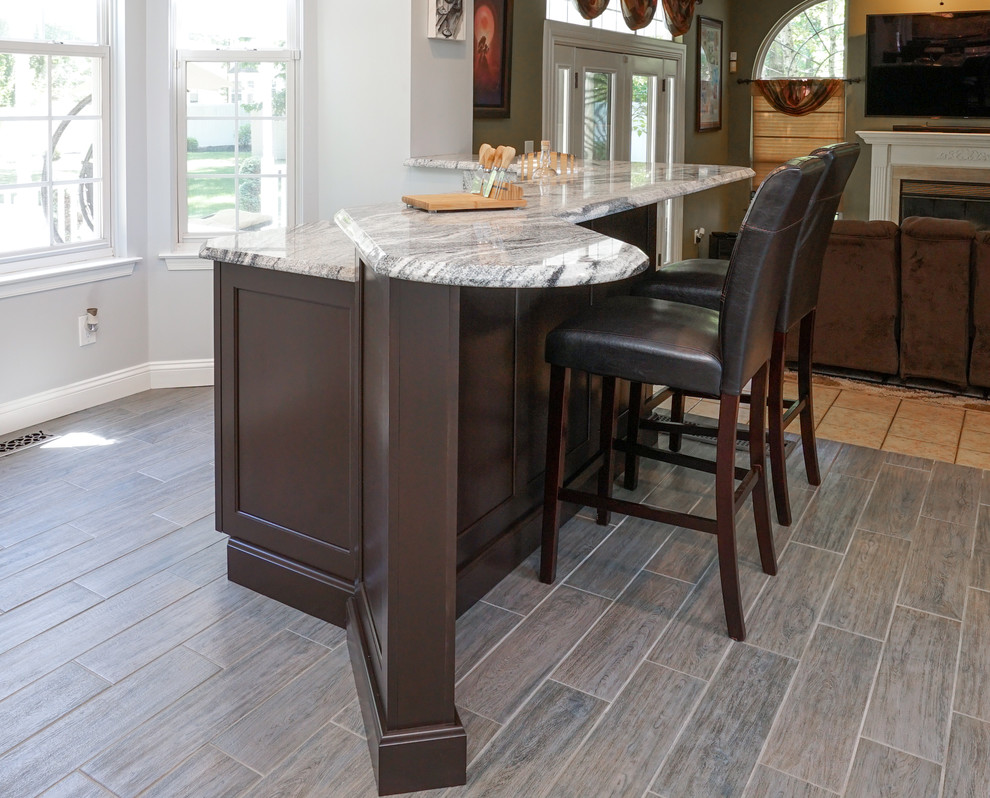 Eat-in kitchen - large transitional l-shaped vinyl floor and brown floor eat-in kitchen idea in Philadelphia with a double-bowl sink, granite countertops, gray backsplash, stone tile backsplash, stainless steel appliances, an island, shaker cabinets and dark wood cabinets