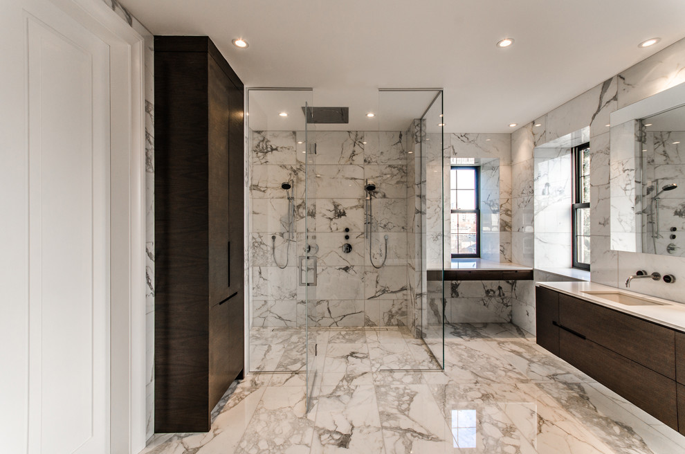 Photo of a large contemporary master bathroom in Montreal with flat-panel cabinets, dark wood cabinets, a curbless shower, an undermount sink, white tile, a freestanding tub, stone tile, white walls, marble floors, solid surface benchtops, a hinged shower door and multi-coloured floor.