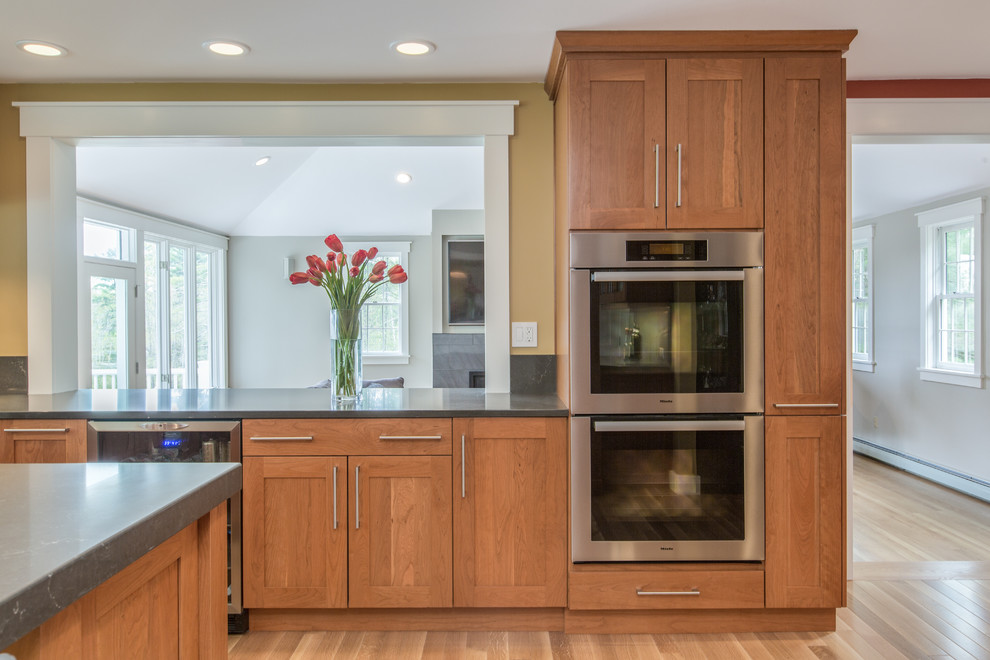 Transitional u-shaped medium tone wood floor kitchen photo in Boston with shaker cabinets, an undermount sink, medium tone wood cabinets, quartz countertops, gray backsplash, stone slab backsplash, stainless steel appliances and an island