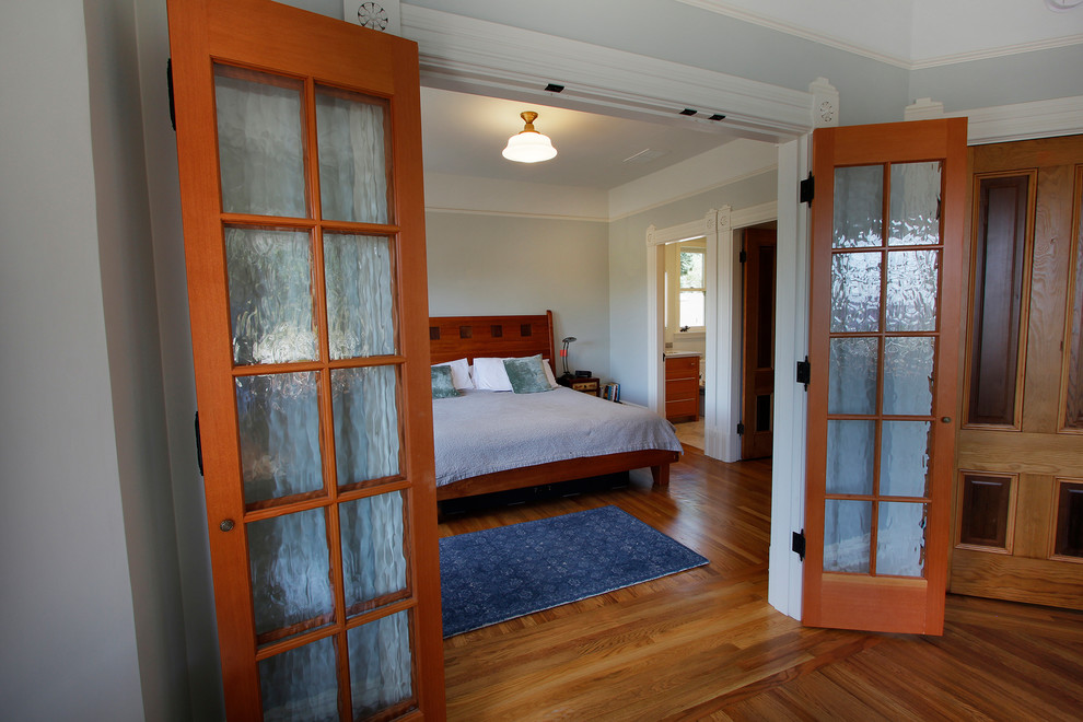 Traditional master bedroom in San Francisco with medium hardwood floors, no fireplace, brown floor and green walls.