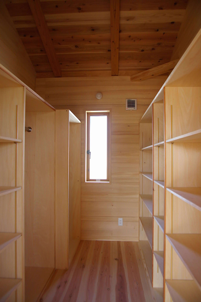 Large asian walk-in wardrobe in Other with light wood cabinets and light hardwood floors.