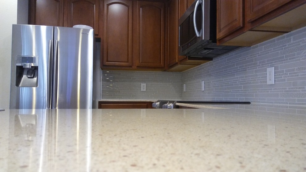 Example of a mid-sized transitional l-shaped eat-in kitchen design with quartz countertops, white backsplash, glass tile backsplash and a peninsula