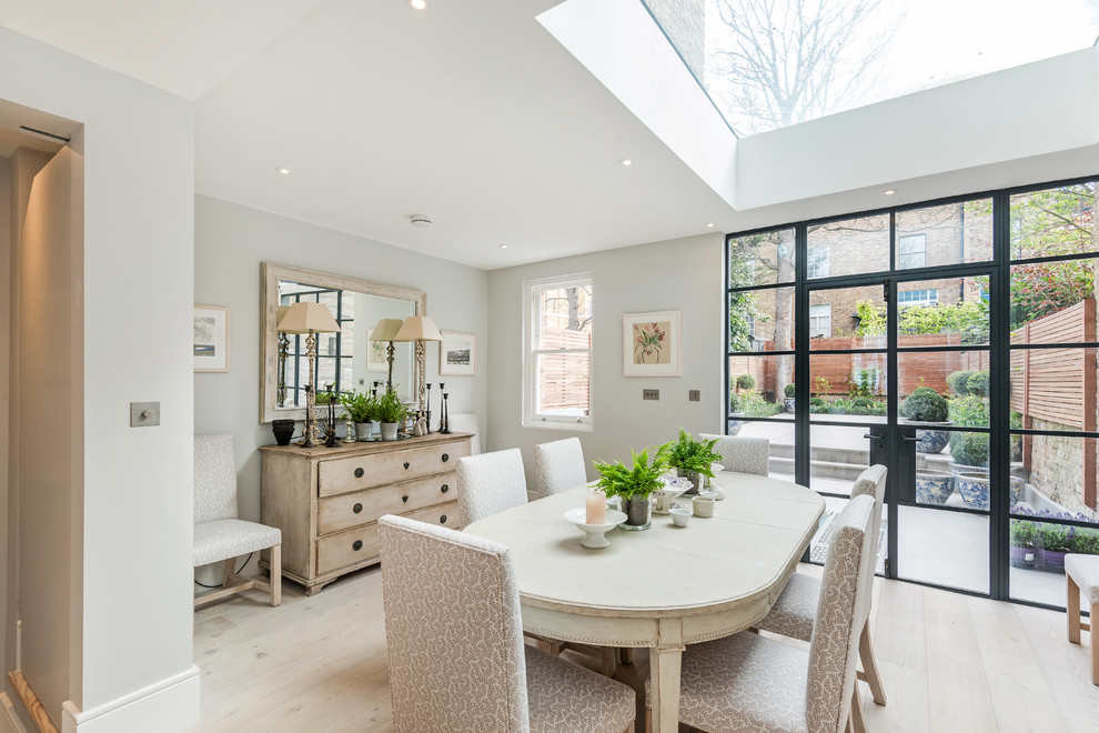 Transitional dining room in London with white walls, light hardwood floors, no fireplace and beige floor.