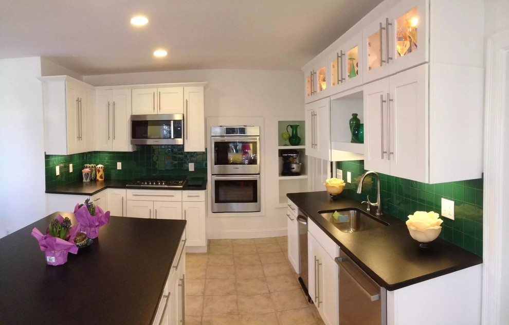 Inspiration for a mid-sized transitional l-shaped ceramic tile enclosed kitchen remodel in Boston with an undermount sink, shaker cabinets, white cabinets, solid surface countertops, green backsplash, ceramic backsplash, stainless steel appliances and an island