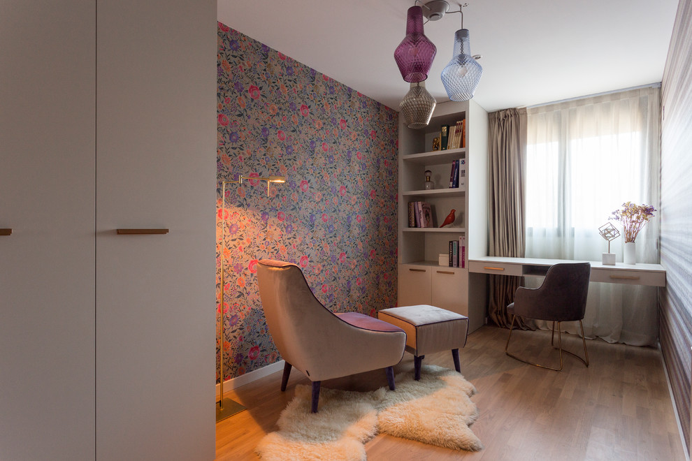 Mid-sized contemporary home office in Barcelona with multi-coloured walls, medium hardwood floors, a built-in desk and brown floor.