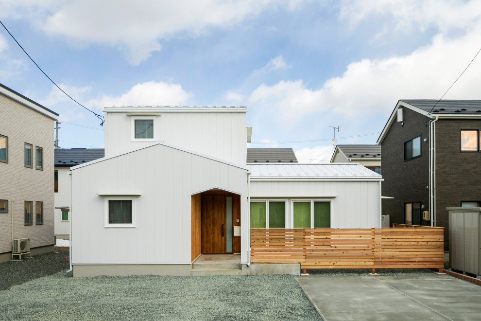 Réalisation d'une façade de maison métallique et blanche nordique de taille moyenne et à un étage avec un toit à deux pans, un toit en métal et un toit blanc.