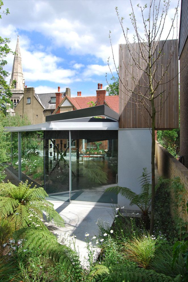 This is an example of a large contemporary two-storey exterior in London with wood siding and a flat roof.