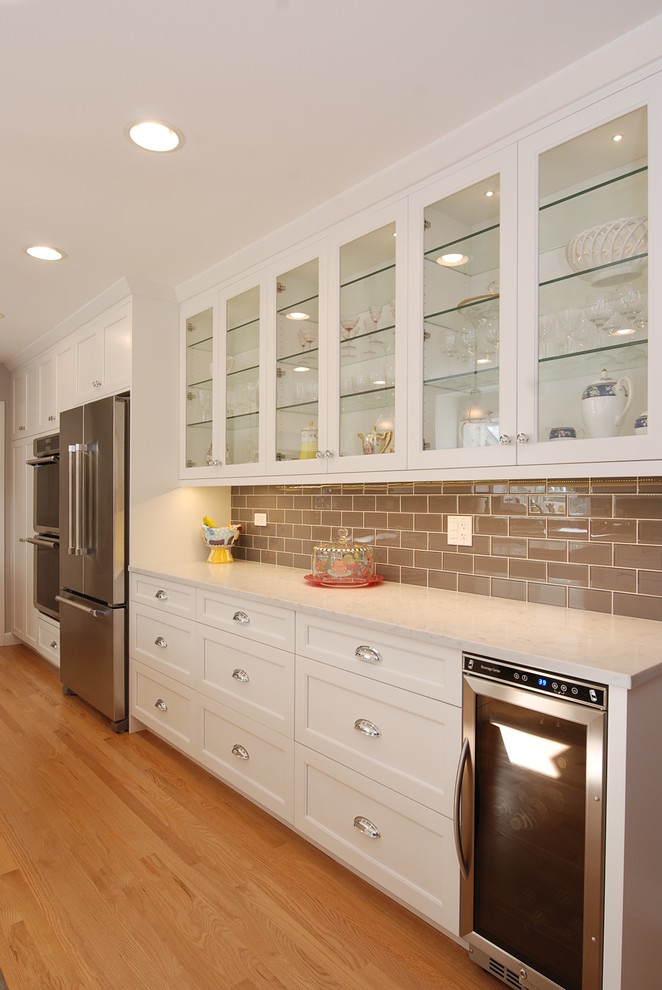 Example of a mid-sized transitional u-shaped light wood floor eat-in kitchen design in Chicago with a single-bowl sink, recessed-panel cabinets, white cabinets, quartzite countertops, gray backsplash, porcelain backsplash, stainless steel appliances and an island