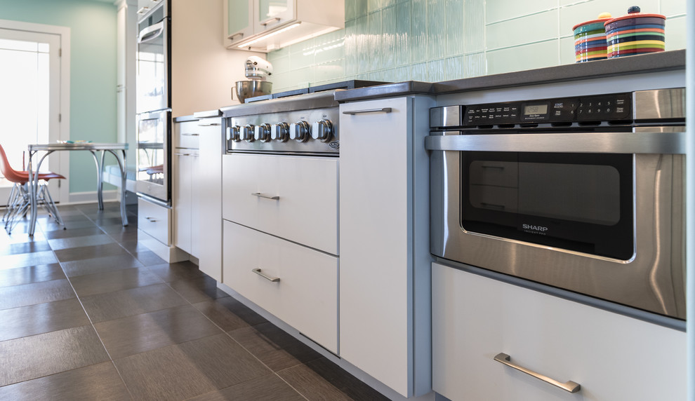 Large modern l-shaped eat-in kitchen in St Louis with an undermount sink, flat-panel cabinets, white cabinets, quartz benchtops, blue splashback, glass tile splashback, white appliances and a peninsula.