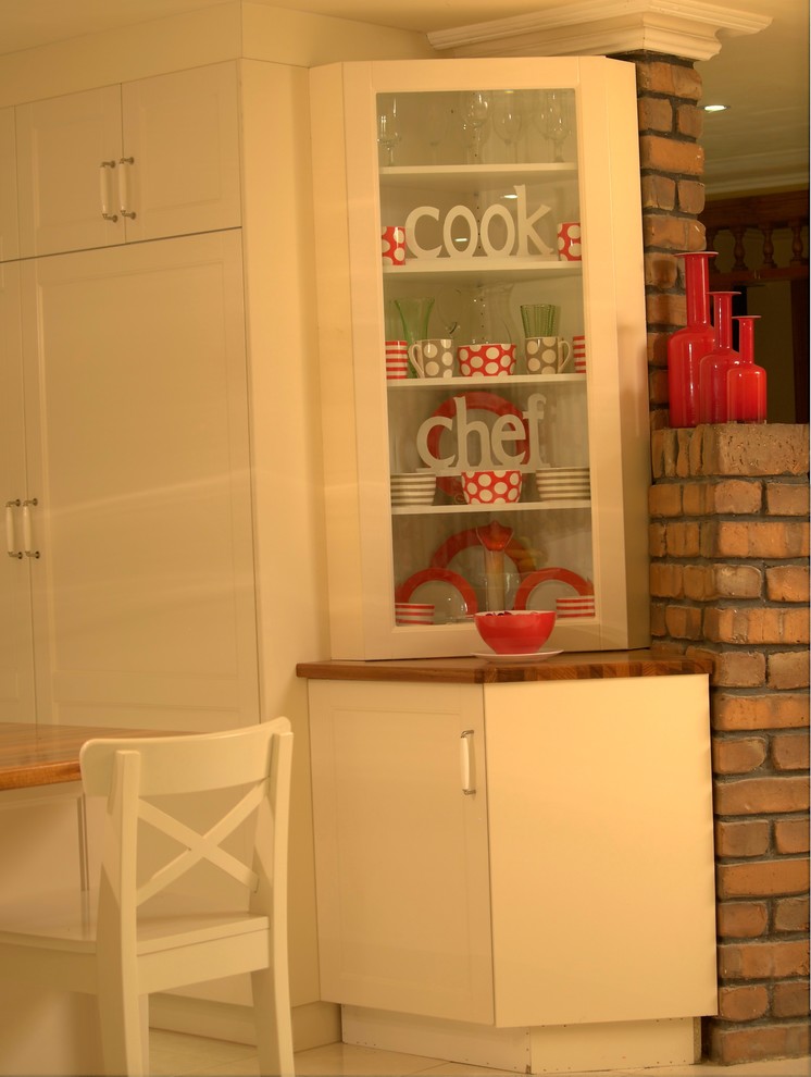 Design ideas for a large country u-shaped kitchen pantry with an undermount sink, shaker cabinets, white cabinets, wood benchtops, metallic splashback, glass sheet splashback, black appliances, terra-cotta floors and with island.