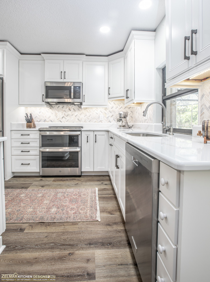 Bild på ett mellanstort nordiskt vit vitt kök, med en enkel diskho, luckor med infälld panel, vita skåp, bänkskiva i kvarts, flerfärgad stänkskydd, stänkskydd i keramik, vinylgolv, en köksö och brunt golv