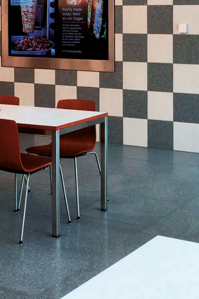 Cette image montre un grand couloir minimaliste avec un mur gris, un sol en terrazzo et un sol gris.